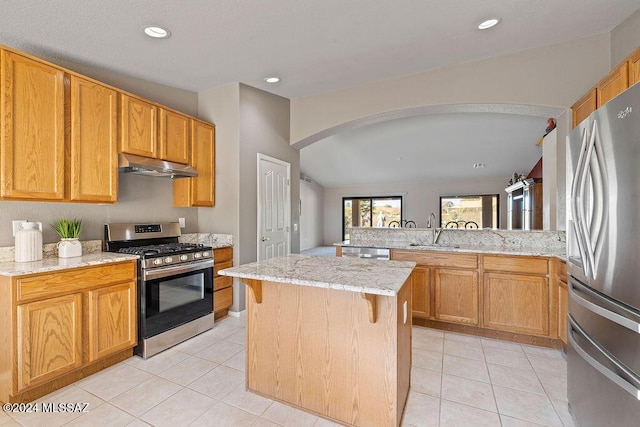 kitchen with sink, a center island, kitchen peninsula, a breakfast bar area, and appliances with stainless steel finishes