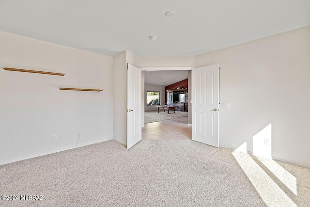 carpeted spare room with vaulted ceiling