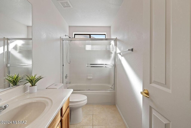 full bathroom with tile patterned flooring, combined bath / shower with glass door, a textured ceiling, toilet, and vanity