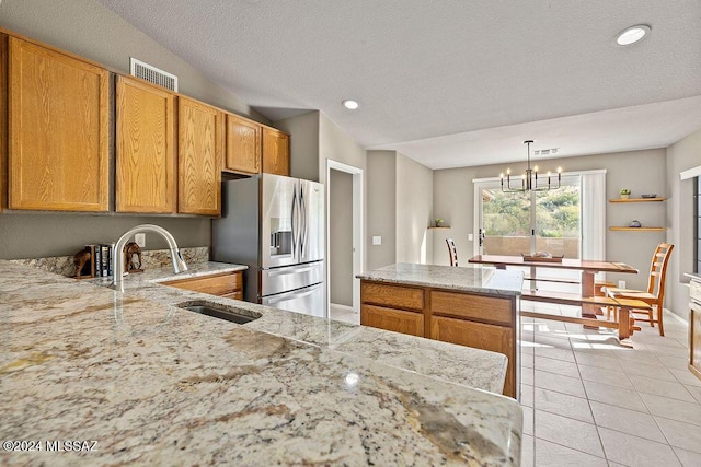 kitchen with sink, stainless steel refrigerator with ice dispenser, a notable chandelier, decorative light fixtures, and light tile patterned flooring