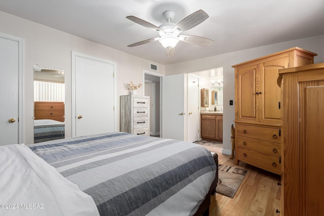 bedroom with ensuite bathroom, light hardwood / wood-style flooring, and ceiling fan