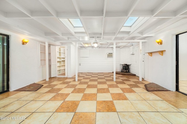 basement with built in shelves, a wall mounted air conditioner, light tile patterned floors, and a wood stove