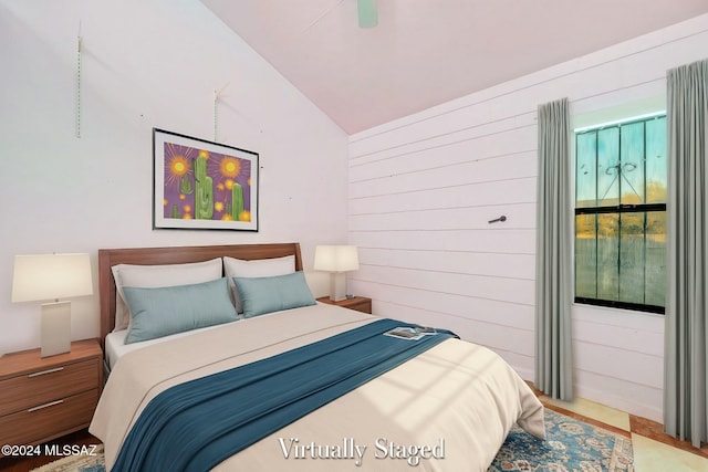 bedroom with ceiling fan, wooden walls, and vaulted ceiling