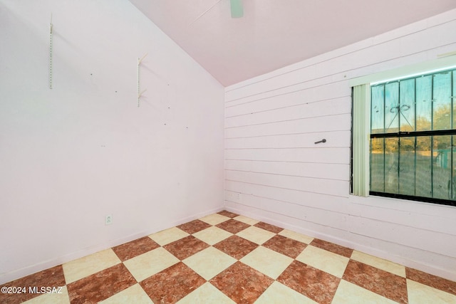 empty room featuring wooden walls and vaulted ceiling