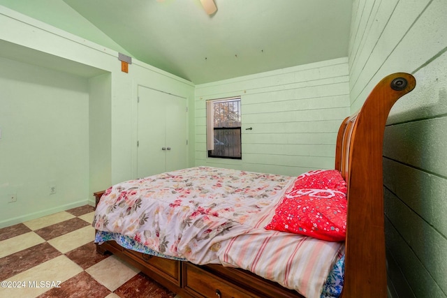 bedroom featuring lofted ceiling and wooden walls