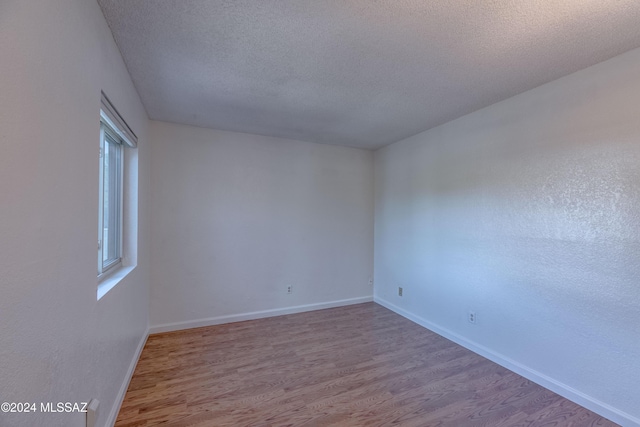 unfurnished room with light hardwood / wood-style flooring, a textured ceiling, and plenty of natural light