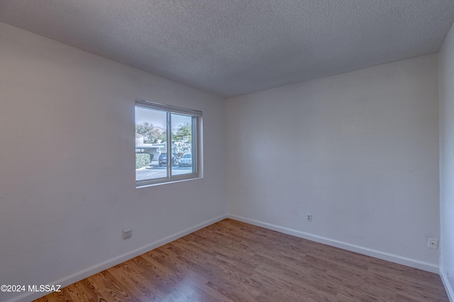 spare room featuring light hardwood / wood-style flooring and a textured ceiling