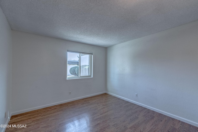 unfurnished room with hardwood / wood-style flooring and a textured ceiling