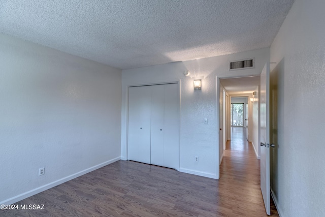 unfurnished bedroom with dark wood-type flooring, a closet, and a textured ceiling