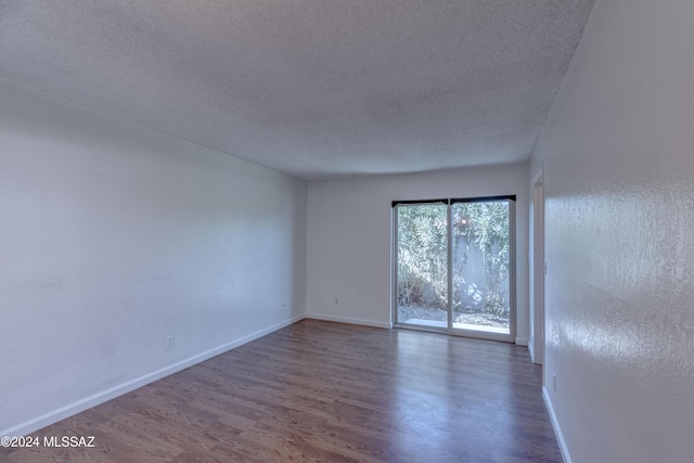 unfurnished room with hardwood / wood-style flooring and a textured ceiling