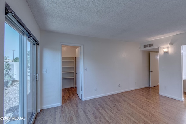 unfurnished room featuring a textured ceiling and light hardwood / wood-style floors