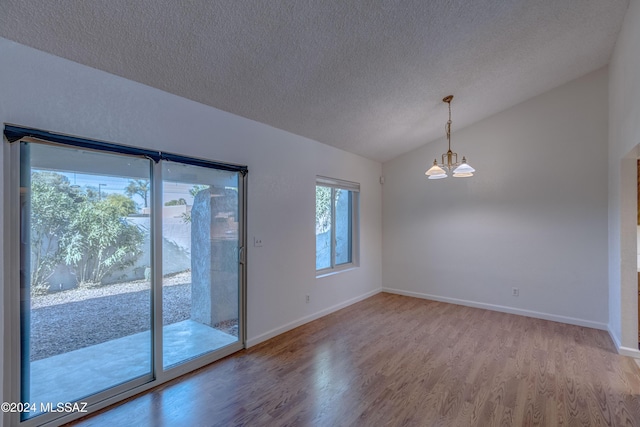 unfurnished room with an inviting chandelier, a textured ceiling, vaulted ceiling, and wood-type flooring