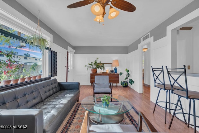 living room featuring ceiling fan, light wood-type flooring, and a wealth of natural light