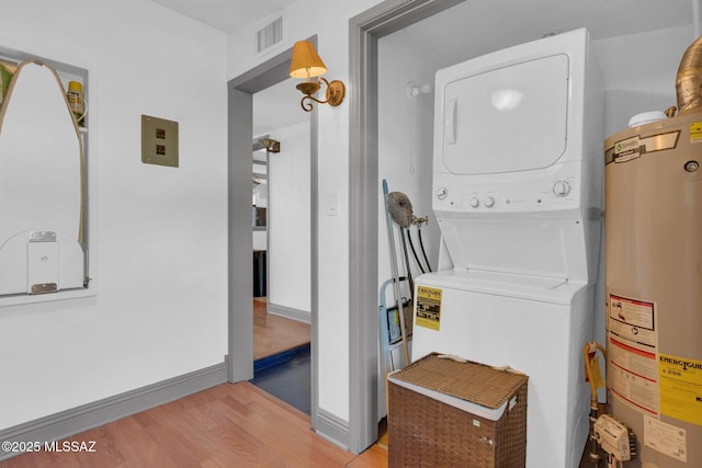 laundry room with stacked washing maching and dryer, light hardwood / wood-style flooring, and water heater