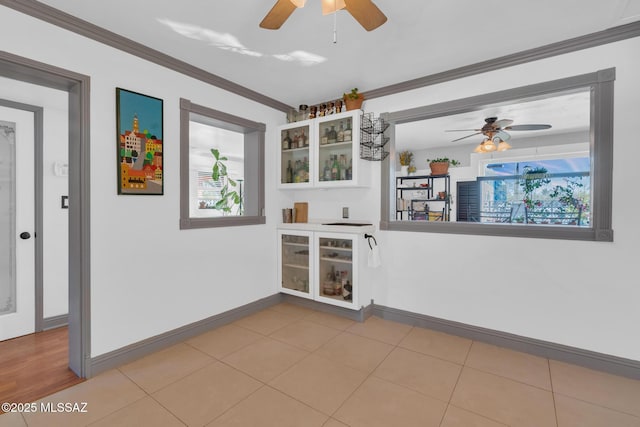 unfurnished room featuring ceiling fan, ornamental molding, and light tile patterned floors