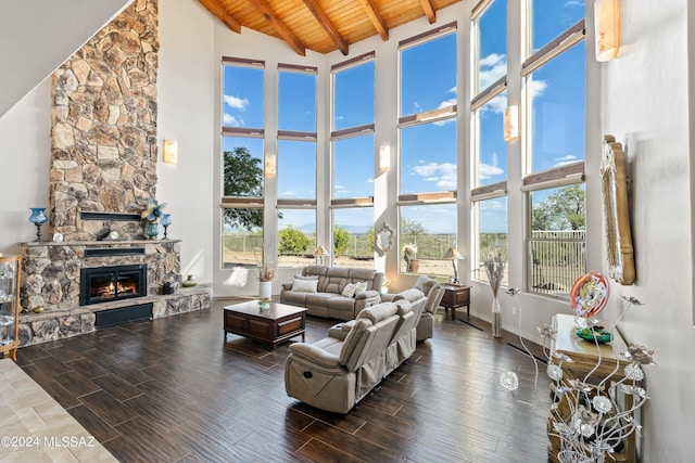 living room with a stone fireplace, plenty of natural light, beamed ceiling, and a towering ceiling