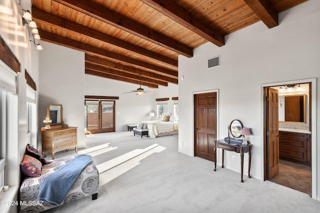 bedroom with connected bathroom, beamed ceiling, light colored carpet, and wooden ceiling