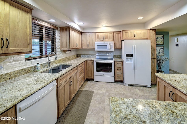 kitchen featuring light tile patterned floors, white appliances, light stone counters, and sink