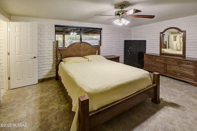 bedroom with ceiling fan and brick wall