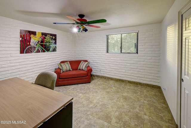 sitting room with tile patterned floors, ceiling fan, and brick wall