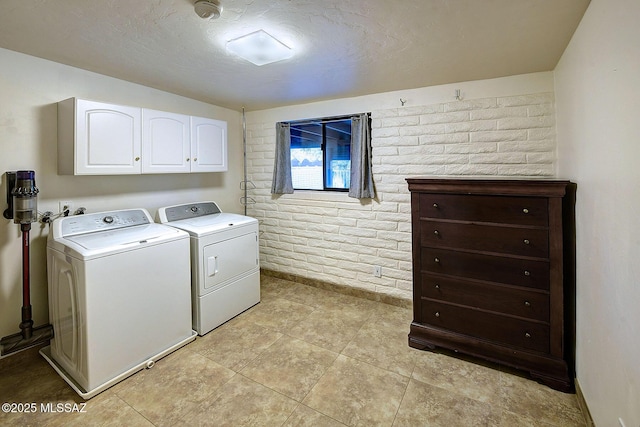 laundry room with cabinets, brick wall, and independent washer and dryer