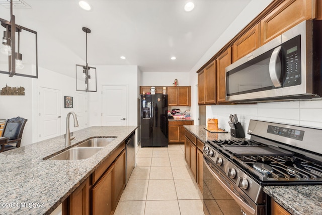 kitchen with sink, stainless steel appliances, light stone counters, decorative light fixtures, and light tile patterned flooring