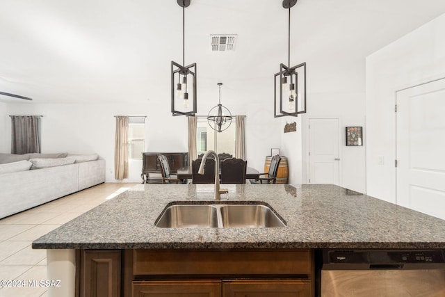 kitchen featuring dark stone countertops, sink, stainless steel dishwasher, and decorative light fixtures