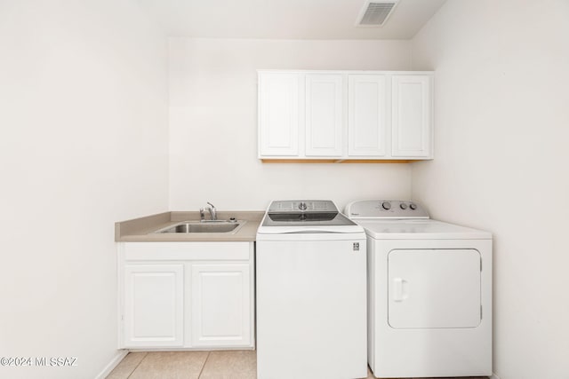 clothes washing area with separate washer and dryer, sink, light tile patterned flooring, and cabinets