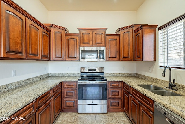 kitchen featuring light tile patterned floors, stainless steel appliances, light stone counters, and sink