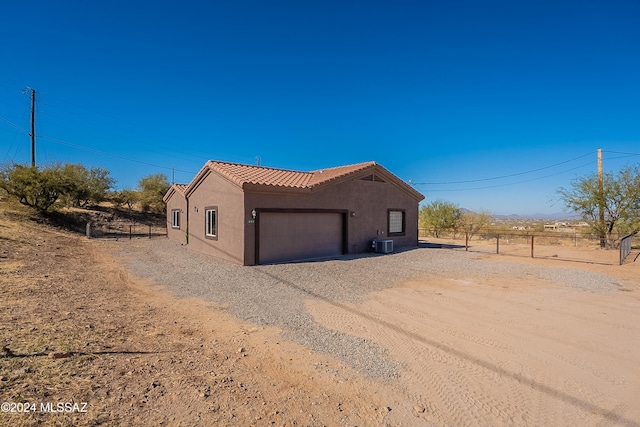 view of side of home with a garage and central air condition unit