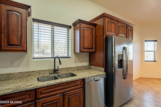 kitchen with light tile patterned flooring, light stone countertops, sink, and appliances with stainless steel finishes