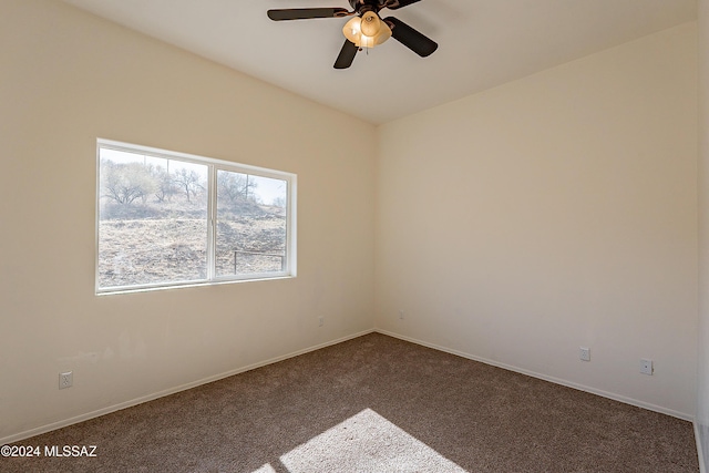 spare room with ceiling fan and dark carpet