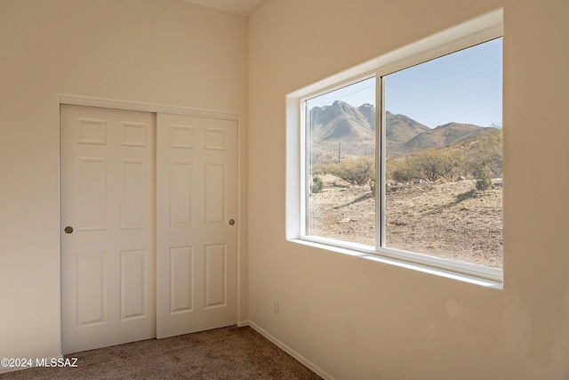 unfurnished bedroom featuring a mountain view, carpet floors, and a closet