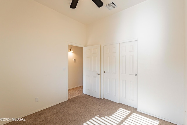 unfurnished bedroom featuring light carpet, a closet, and ceiling fan