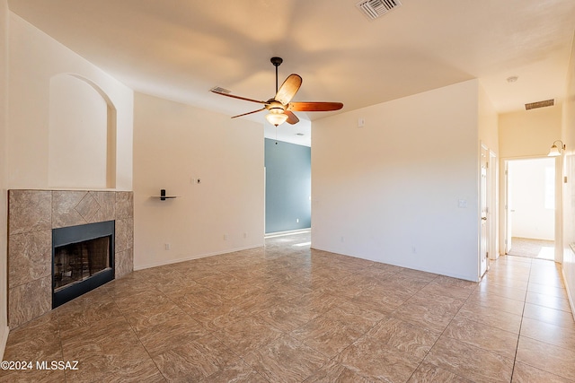 unfurnished living room featuring a tile fireplace and ceiling fan