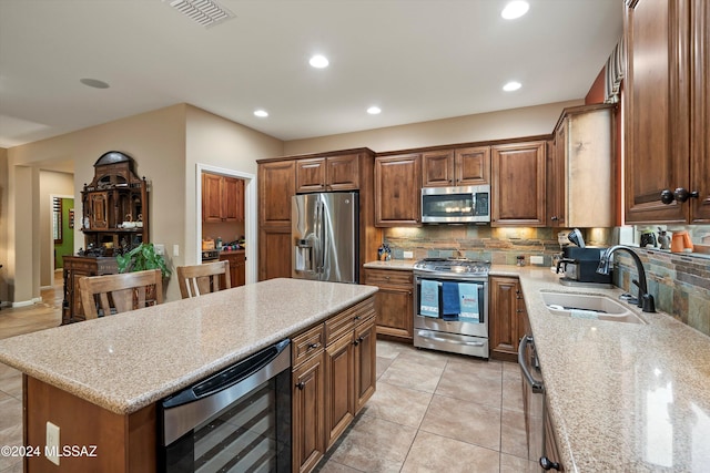 kitchen featuring light stone counters, sink, a kitchen island, and stainless steel appliances