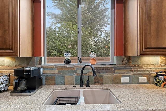 kitchen featuring tasteful backsplash, light stone counters, sink, and a healthy amount of sunlight