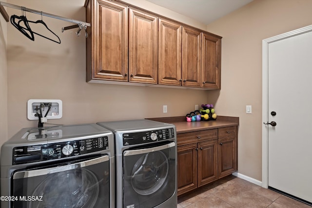 washroom with cabinets, light tile patterned flooring, and washing machine and clothes dryer