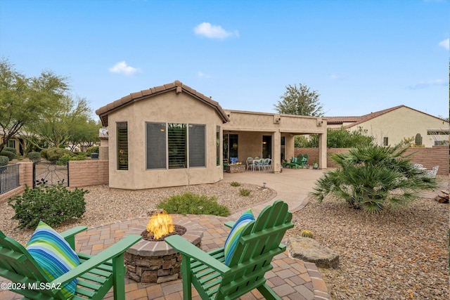 rear view of property featuring a patio and a fire pit