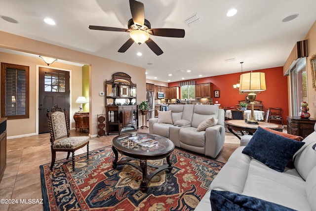 tiled living room featuring ceiling fan with notable chandelier