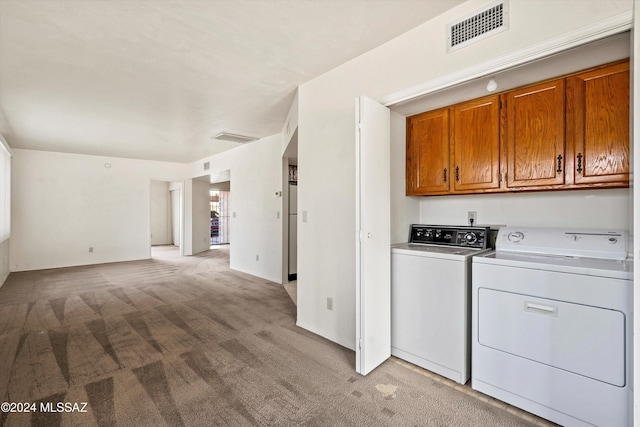 laundry area featuring separate washer and dryer, light colored carpet, and cabinets