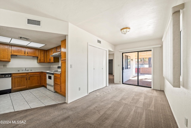 kitchen featuring sink, white appliances, and light carpet