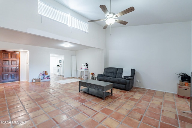 tiled living room with ceiling fan and a high ceiling