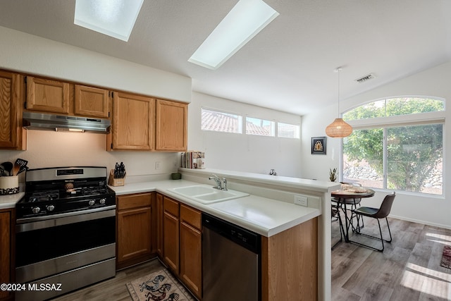 kitchen with kitchen peninsula, decorative light fixtures, stainless steel appliances, and sink