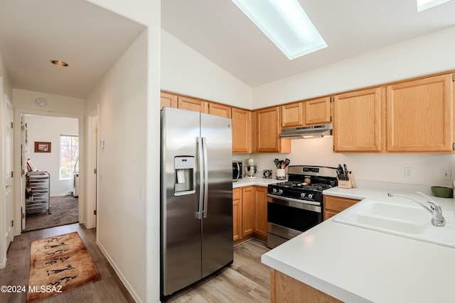 kitchen featuring sink, vaulted ceiling, light hardwood / wood-style flooring, light brown cabinetry, and stainless steel appliances