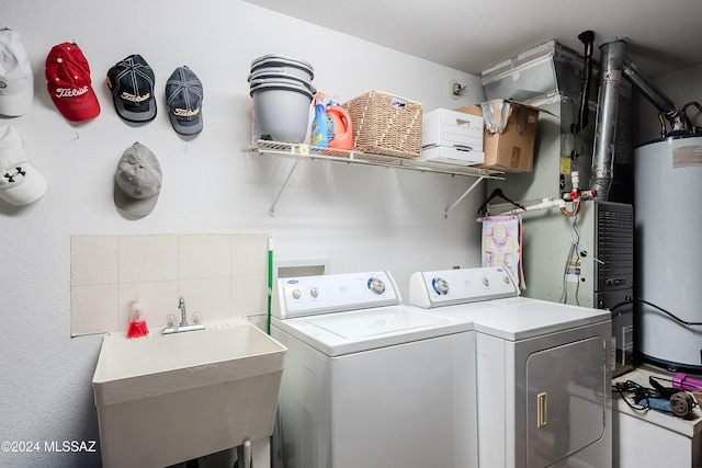 clothes washing area with washer and clothes dryer, gas water heater, and sink