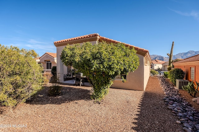 rear view of house with a mountain view, a patio, and central AC