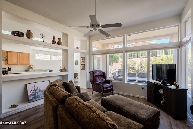 living room with ceiling fan, built in features, a healthy amount of sunlight, and dark hardwood / wood-style floors