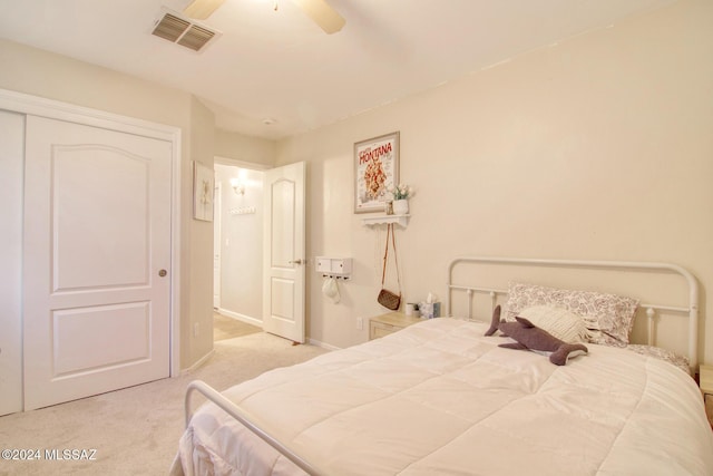 bedroom with ceiling fan, light colored carpet, and a closet