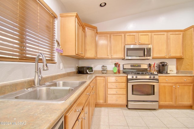 kitchen with stainless steel appliances, sink, light tile patterned floors, light brown cabinets, and lofted ceiling